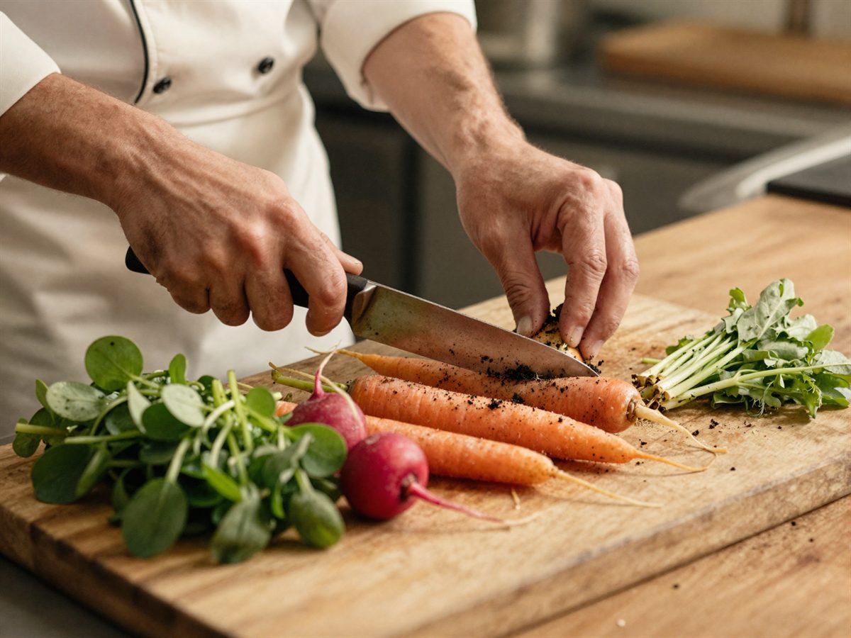 Hands trimming fresh market vegetables on a wooden board in the kitchen